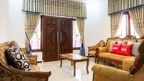 A spacious living room with a wooden coffee table, two sofas, and a large wooden door. - OYO 2169  Anugrah Bromo Homestay (Wonokitri)