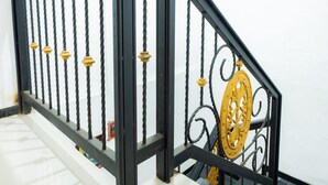 A staircase with black railings and golden decorative elements. - OYO 2169  Anugrah Bromo Homestay (Wonokitri)