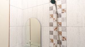 Un baño con ducha, repisa de vidrio y espejo.
