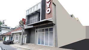 Un edificio con un cartel llamativo de 'OYO', una entrada con puerta y un balcón.