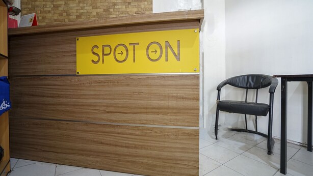 Um balcão de recepção com uma placa que diz 'SPOT ON' e uma cadeira preta à direita.