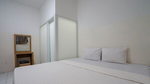 Quarto com uma cama grande, uma mesa de cabeceira de madeira, um espelho e uma porta de correr.
