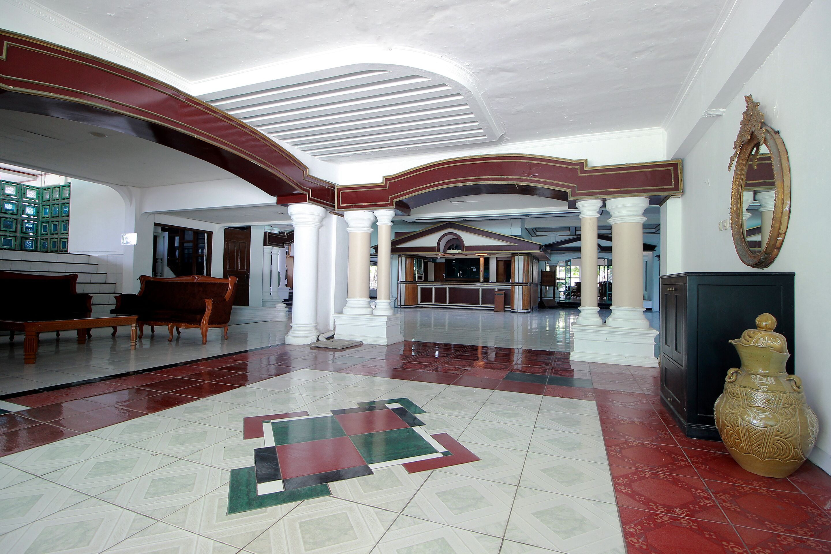 Un hall d’entrée spacieux, doté d’un sol à motifs géométriques, d’un grand piano et d’un grand vase décoratif.