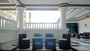 Un vestíbulo con suelo a cuadros, columnas blancas y muebles de mimbre.