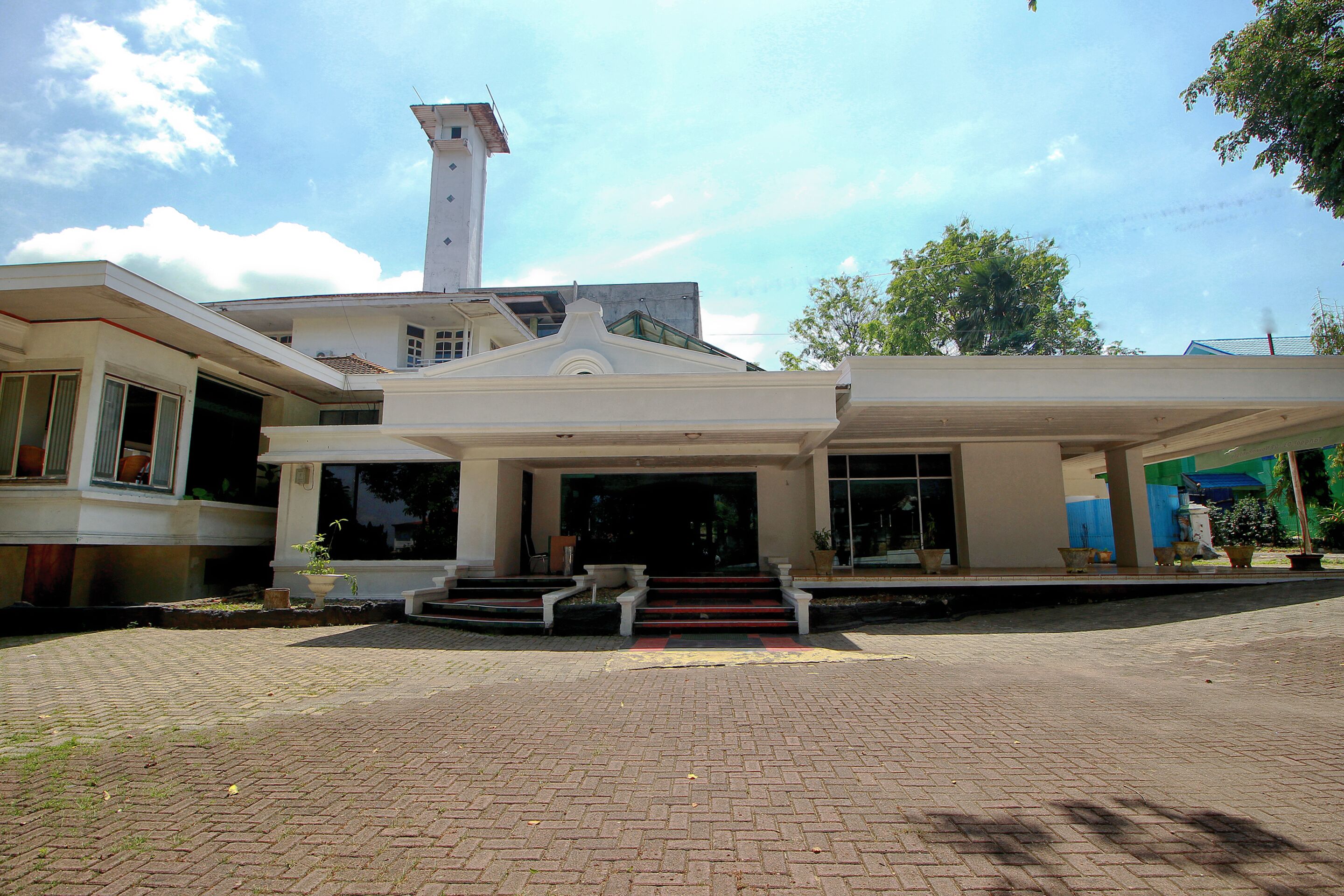 A large, modern building with a prominent entrance, a tall tower, and a paved driveway.