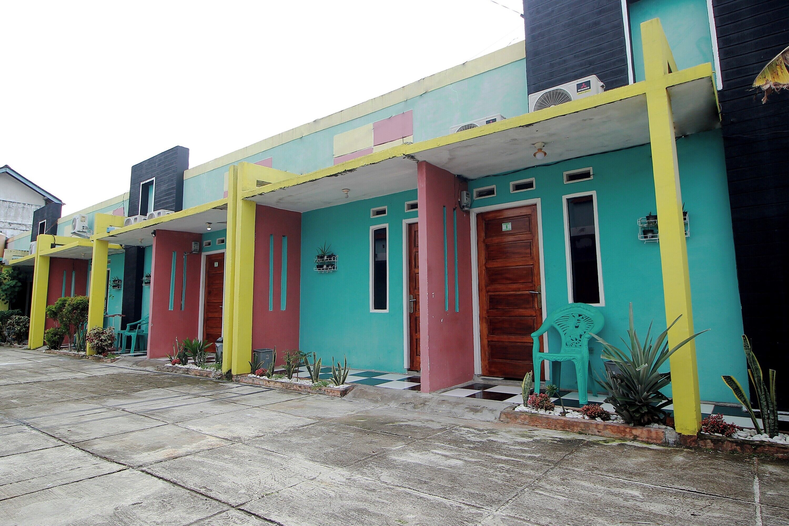 A row of colorful buildings with distinct doorways and windows, some with air conditioning units.