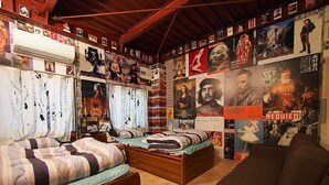 A room with two beds, a sofa, and a wall covered with posters and pictures.