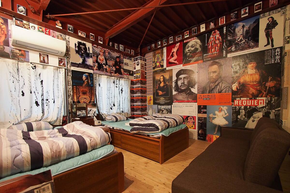 Ein Zimmer mit zwei Betten, einem Sofa und einer Wand voller Plakate und Bilder.