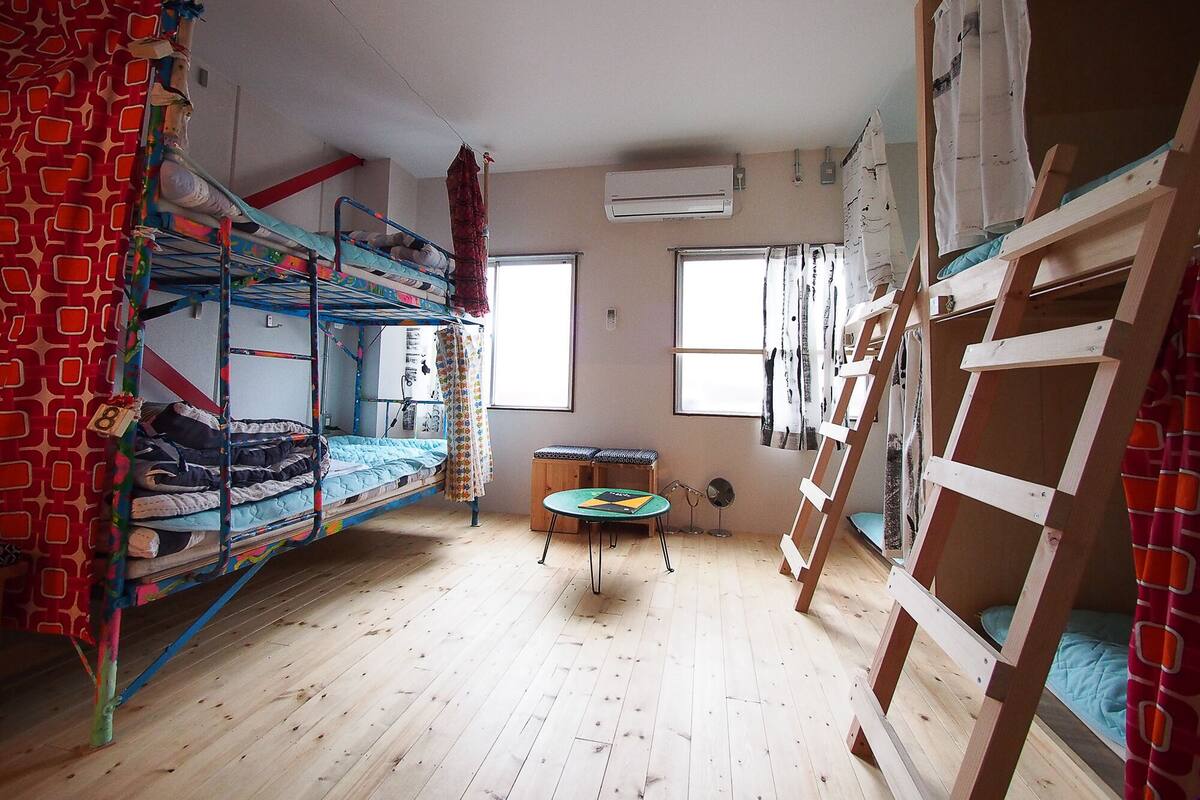 Ein Schlafsaalzimmer mit Etagenbetten, einem kleinen Tisch und einem Fenster.
