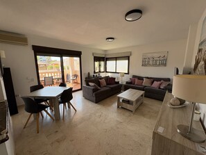 A living room with a dining area, a sofa set, a coffee table, and a lamp. - Superb 3 bedroom apartment in the Golf of Las Ramblas (Orihuela)