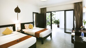 Une chambre d’hôtel avec deux lits, un bureau et une vue sur l’extérieur.