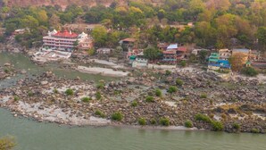 Une ville riveraine, avec des bâtiments qui bordent le cours d’eau, des berges rocheuses et une végétation luxuriante en arrière-plan.