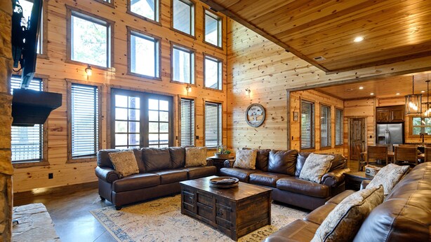 A spacious living room with leather sofas, a coffee table, and a large rug.