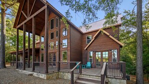 A large log cabin with multiple windows and a deck area.