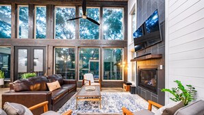 Amplia sala de estar con chimenea, ventanas grandes y ventilador de techo.