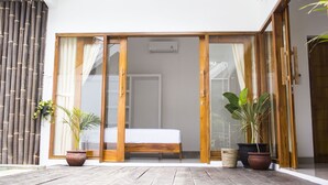 A room with a bed, sliding glass doors, and potted plants. - Watukarung Prapto Homestay (Sendang)