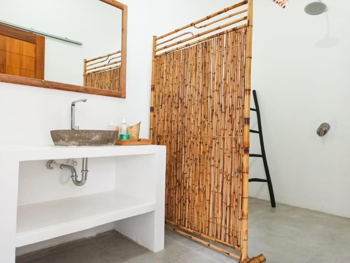 A bathroom with a white sink, mirror, and bamboo shower curtain.
