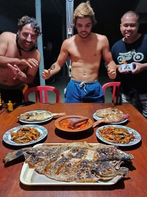 A dining table with various dishes, including grilled fish and other food items. - Watukarung Prapto Homestay (Sendang)