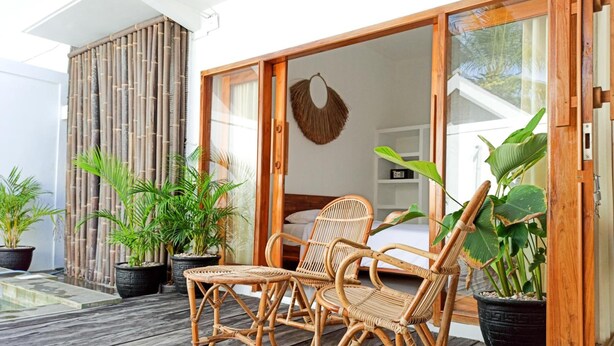 A wooden deck with wicker furniture and potted plants. - Watukarung Prapto Homestay (Sendang)