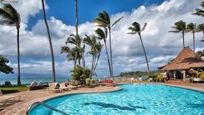 A swimming pool with lounge chairs and palm trees, surrounded by a tropical landscape. - Napili Shores G157 Studio Bedroom Condo by RedAwning (Lahaina)
