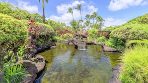 A serene garden with a small stream, lush greenery, and palm trees. - Napili Shores G157 Studio Bedroom Condo by RedAwning (Lahaina)