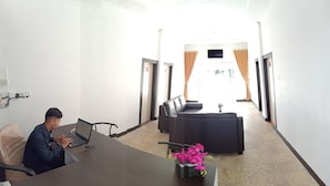 A conference room with a long table, a sofa, and a TV screen. - Hotel Salma (Bukittinggi)