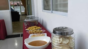 A buffet table with various dishes, a jar of flatbread, and a window with blinds. - Hotel Salma (Bukittinggi)