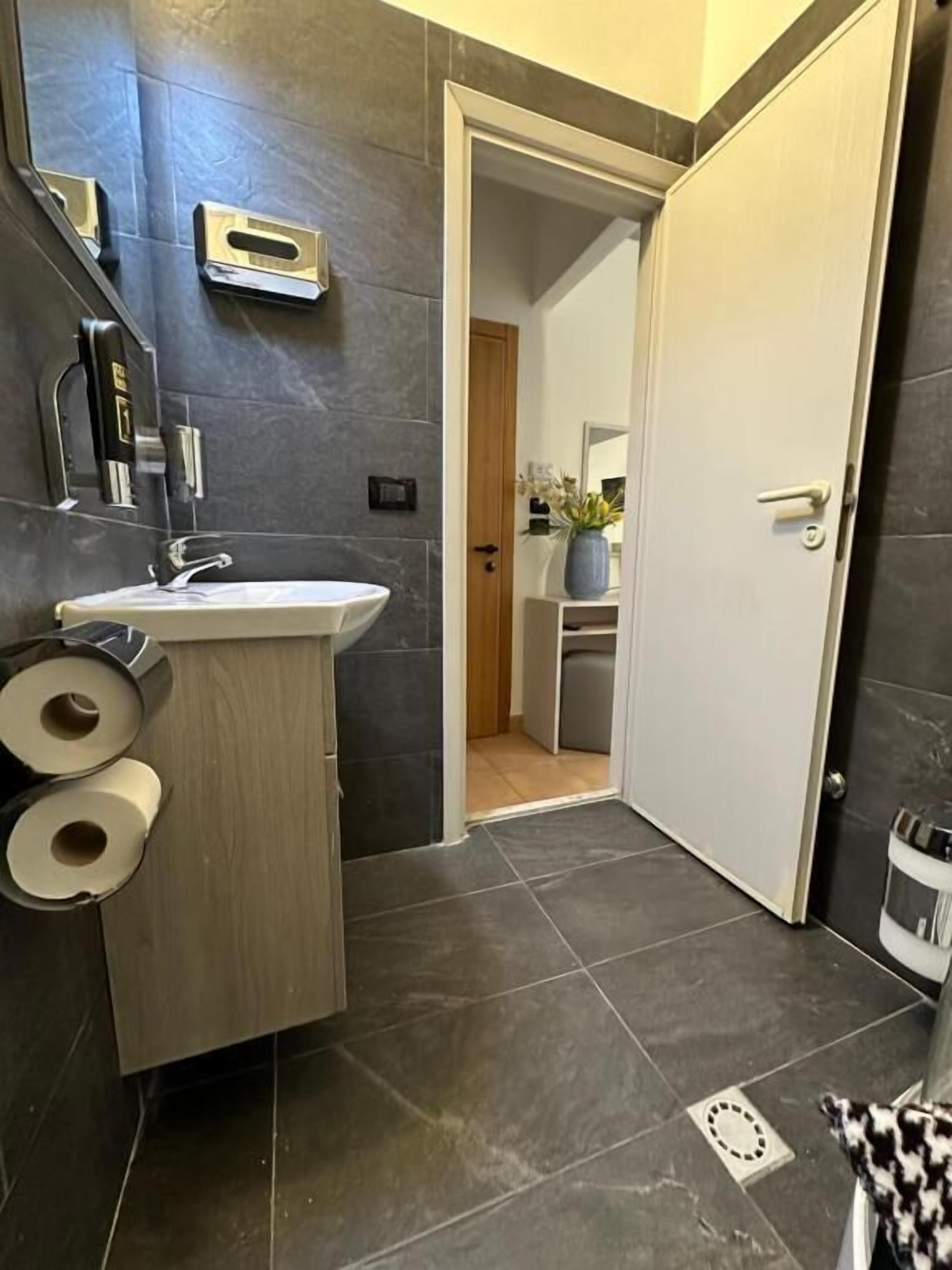 A modern bathroom with a sink, toilet paper, and a mirror.