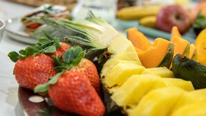 Une table garnie de divers fruits et légumes, notamment des fraises, un ananas et un melon.