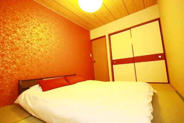A bedroom with a bed, a wooden ceiling, and a wardrobe.