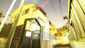 A narrow alleyway with a gated entrance, a yellow building, and a metal fence. - Hotel-Ikoi-Komagome 202 (Tokyo)