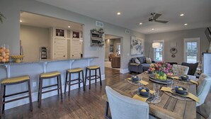 A spacious living area with a wooden dining table set for four, a kitchen with a bar area, and a seating area with a sofa and chairs. - Renovated Craftsman House w/ Patio & Fire Pit! (Vevay)