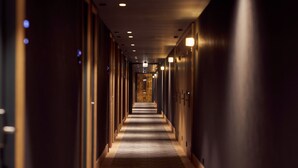 A long, narrow hotel corridor with doors on both sides, recessed lighting, and a carpeted floor. - Met Hotel Amsterdam (Amsterdam)