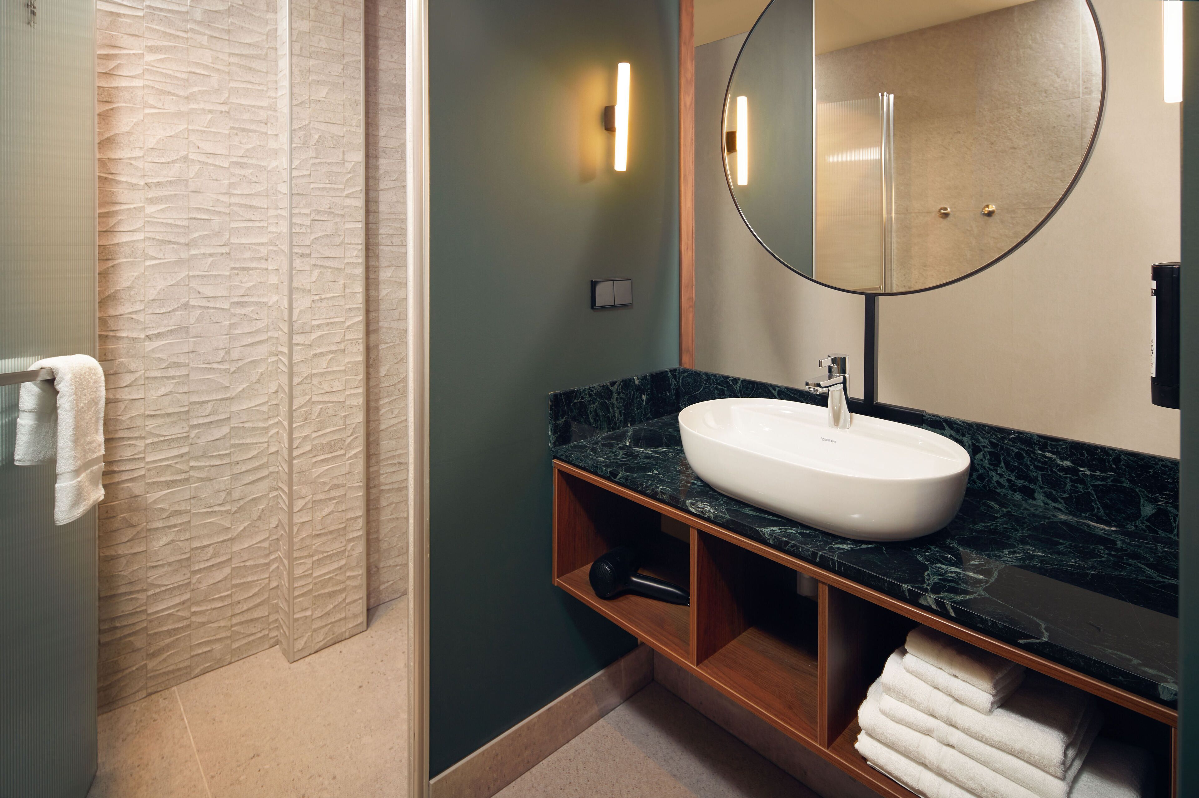 A bathroom with a marble sink, a large mirror, and a towel rack.