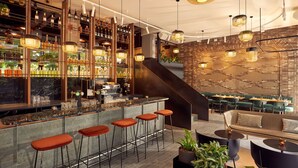 A modern bar area with a bar counter, stools, and a variety of bottles and glasses. - Met Hotel Amsterdam (Amsterdam)