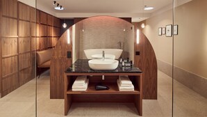 A modern bathroom with a large freestanding sink, wooden cabinetry, and a mirror with framed artwork. - Met Hotel Amsterdam (Amsterdam)