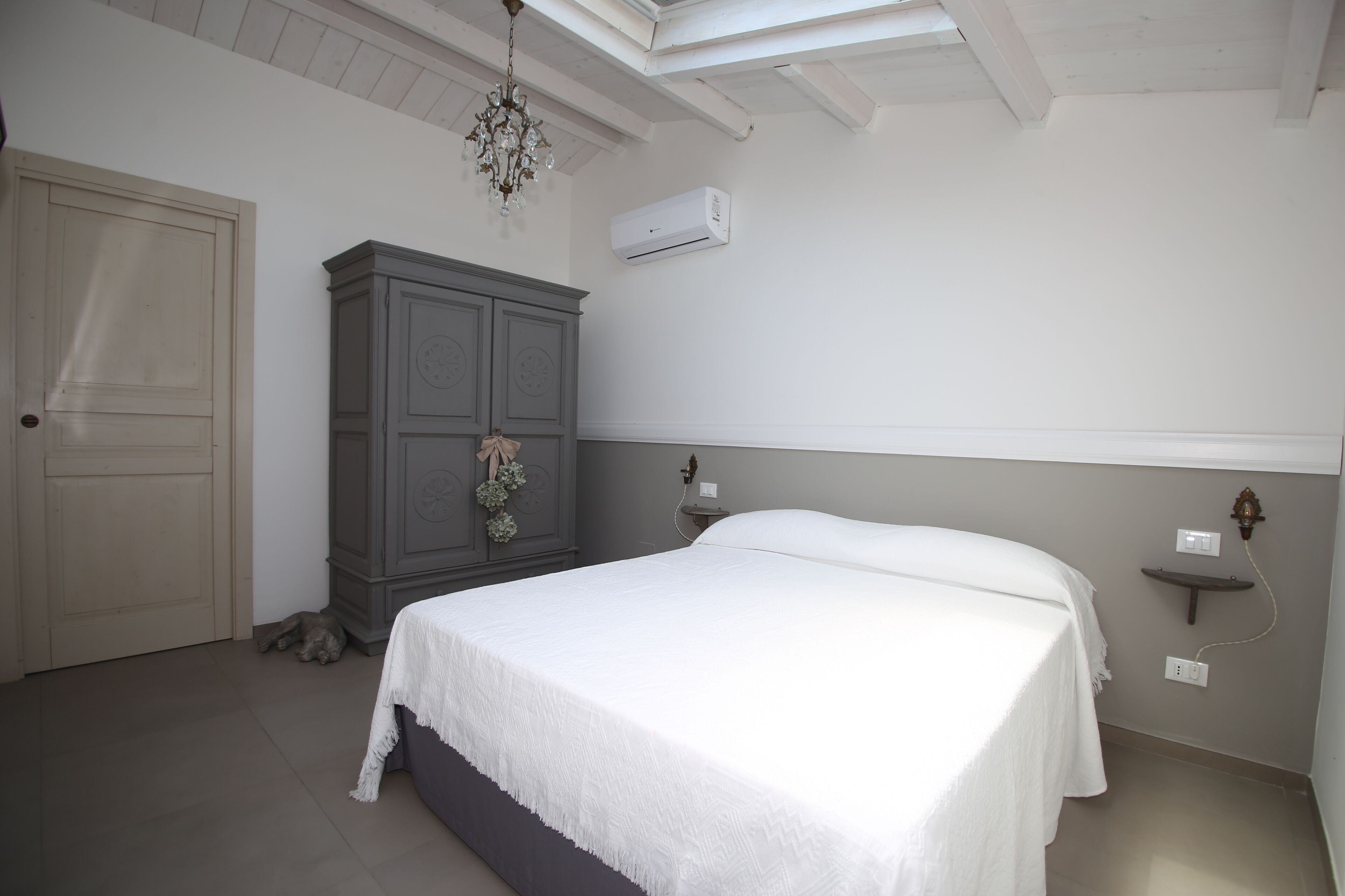Un dormitorio con cama, armario, unidad de aire acondicionado y candelabro.