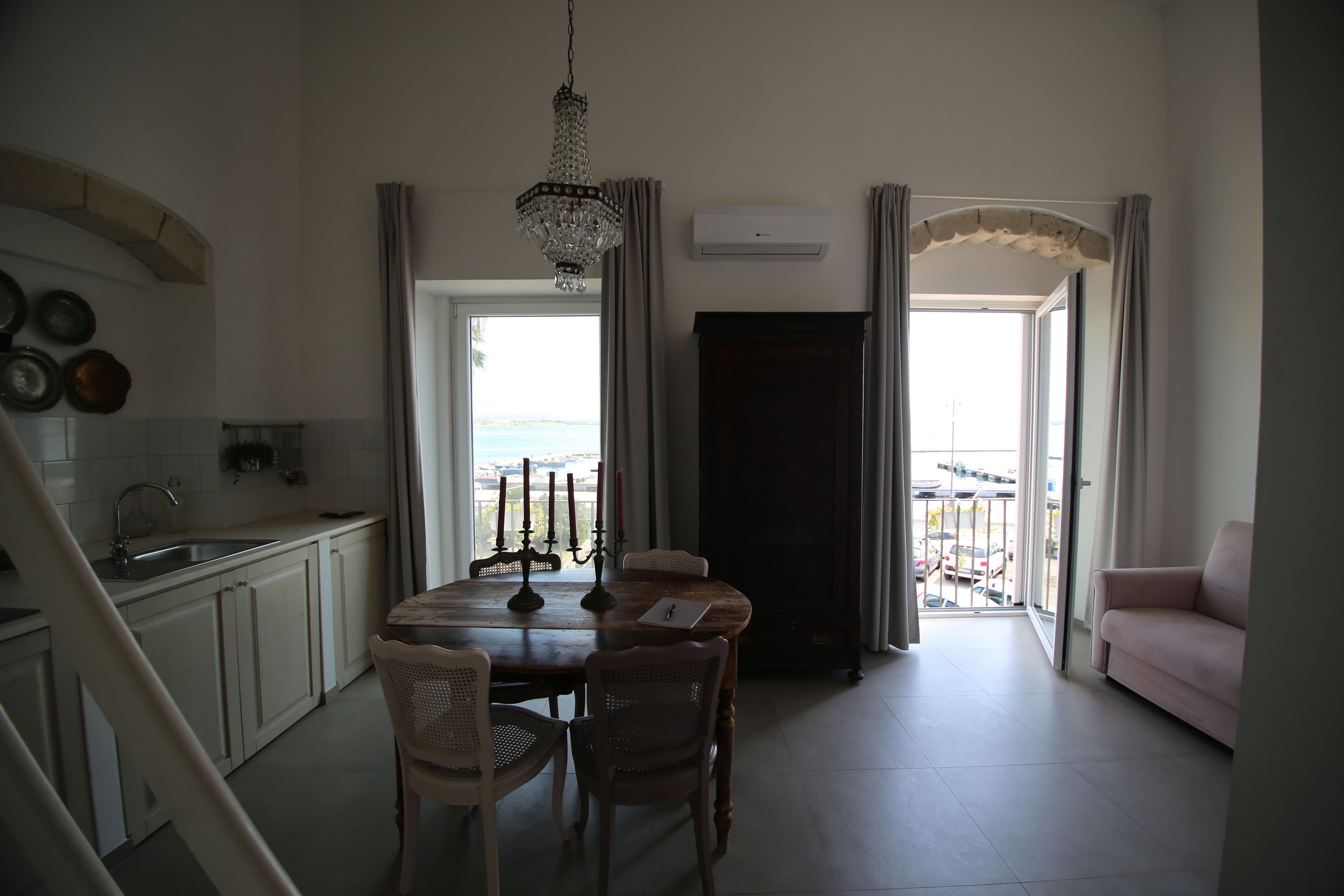 Un amplio espacio habitable con una mesa de comedor, sillas, una araña y un sofá.