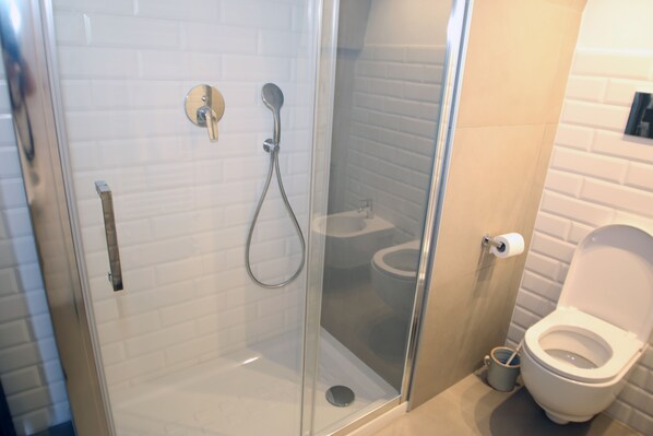 Une salle de bain moderne dotée d’une douche à parois de verre, de toilettes et d’un bidet.