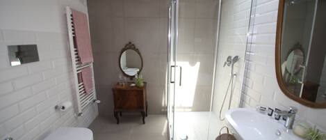 Une salle de bain comprenant des toilettes, un lavabo, une douche et un meuble-lavabo avec un miroir.