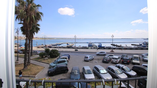Un parking rempli de voitures, avec vue sur la plage et les bateaux.