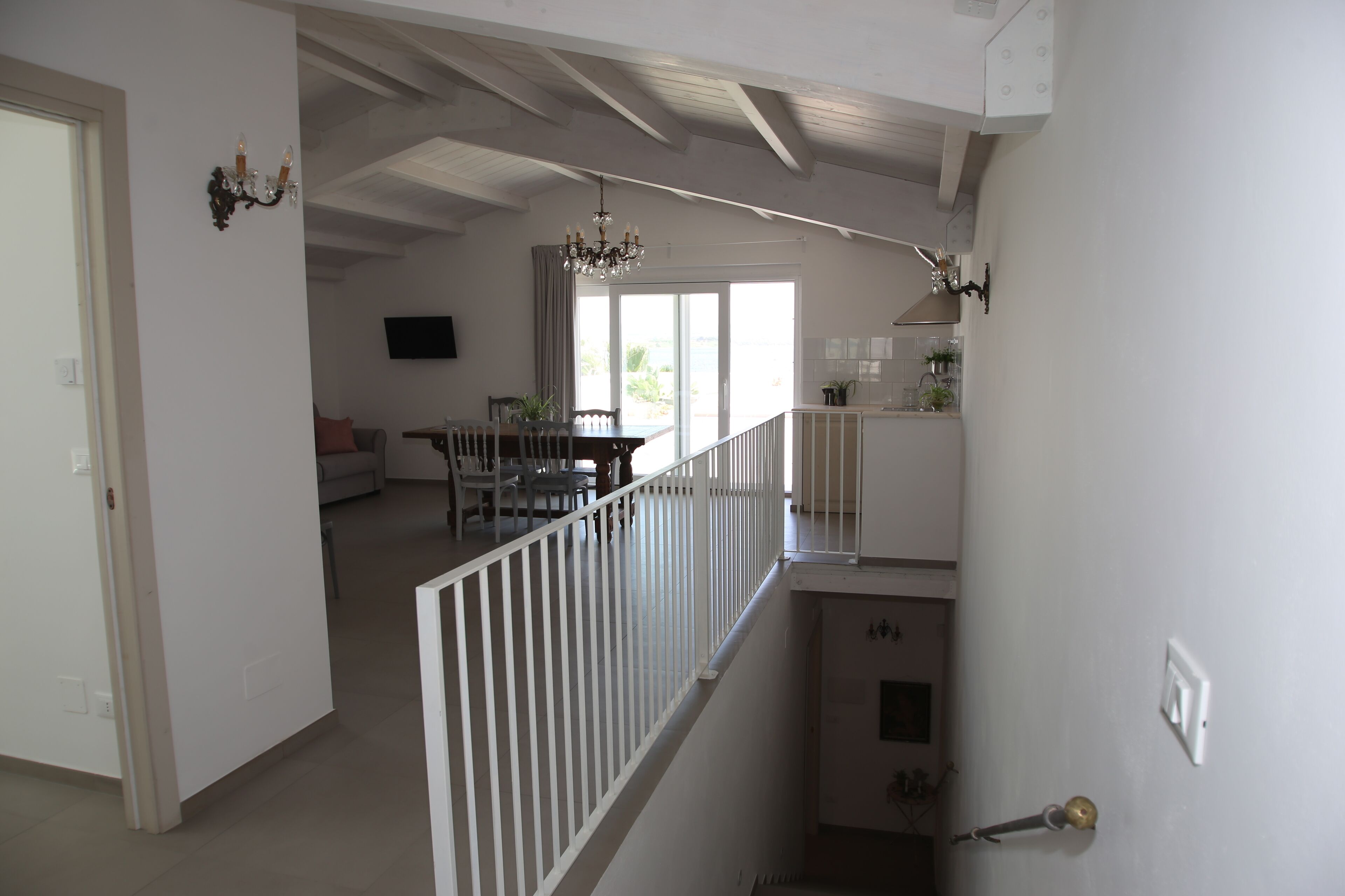 Uma sala de estar ampla com uma mesa de jantar, cadeiras e uma escada que dá acesso a um andar superior.