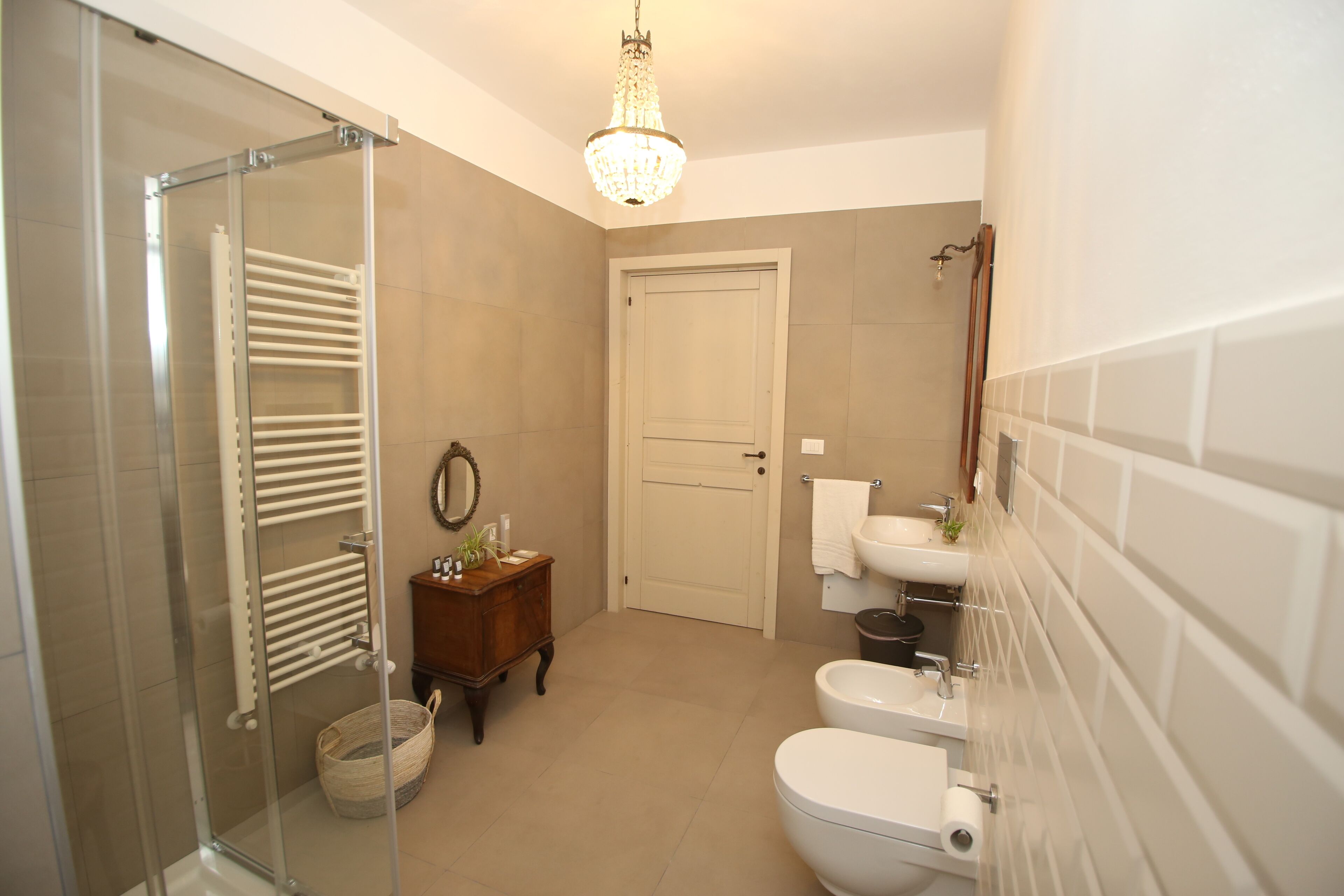 A bathroom with a glass shower enclosure, a wooden vanity, a sink, and a toilet.