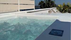 Une piscine avec une eau cristalline, une terrasse blanche et une vue sur les palmiers et l’océan.