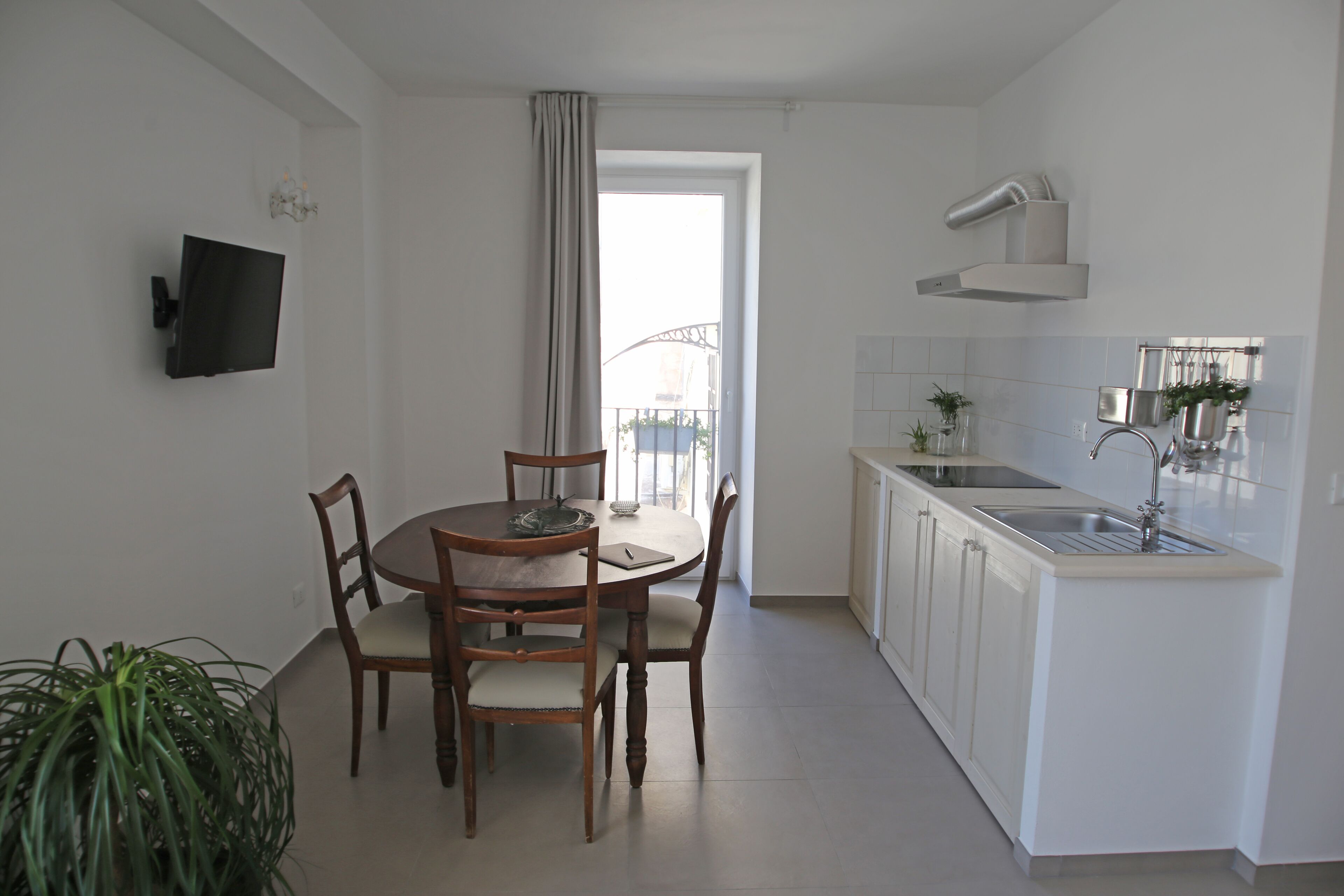 A modern kitchen with white cabinets, a built-in sink, and a dining area with wooden chairs and a table.