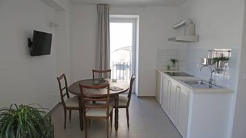 A modern kitchen with white cabinets, a built-in sink, and a dining area with wooden chairs and a table.