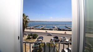 Une vue depuis un balcon donnant sur une marina où sont garées des voitures et des bateaux.