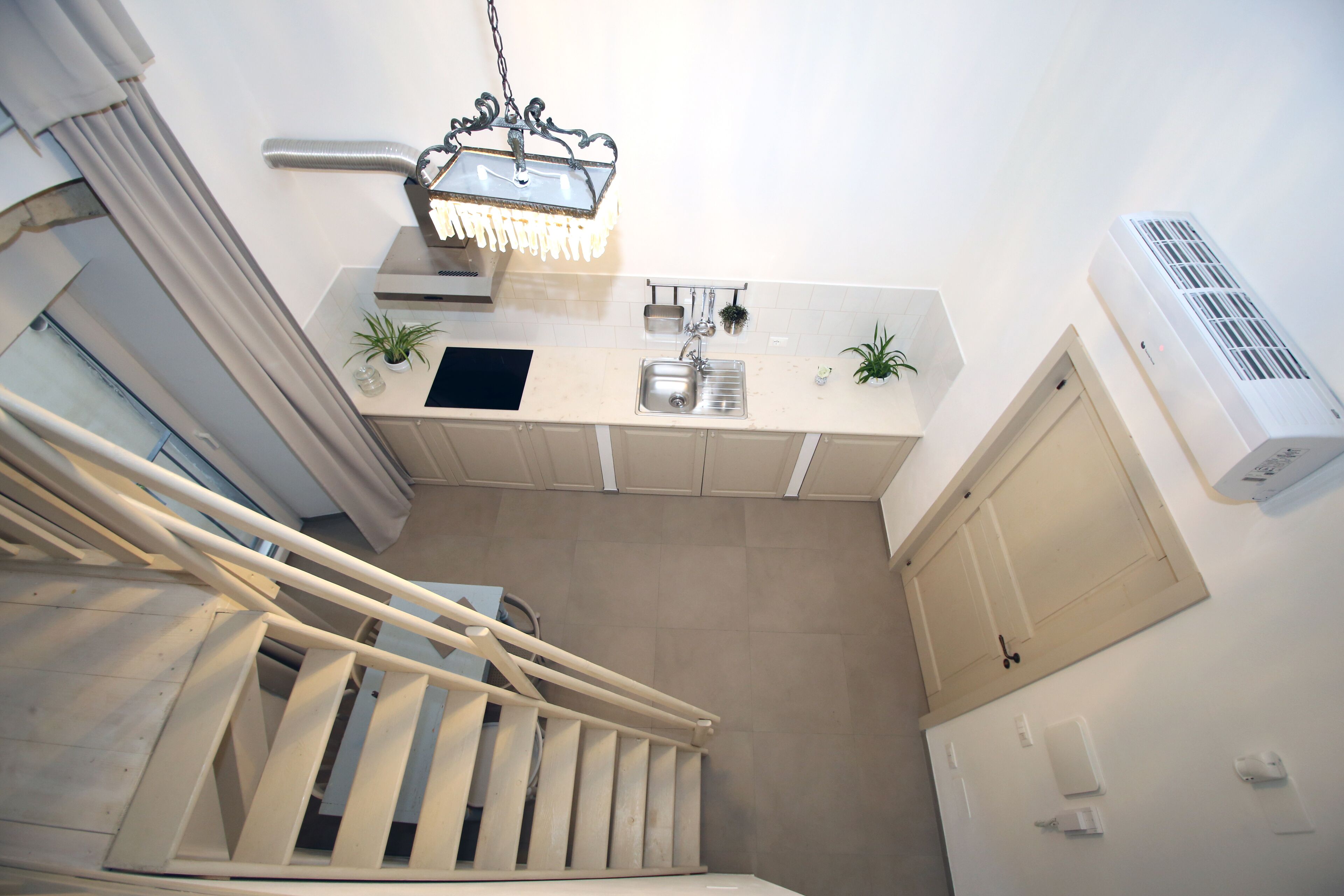 A kitchen with a built-in sink, a hanging light fixture, and an air conditioning unit.