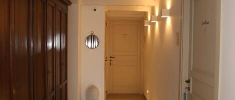 Un pasillo con un armario de madera, un espejo redondo y una puerta con placa.