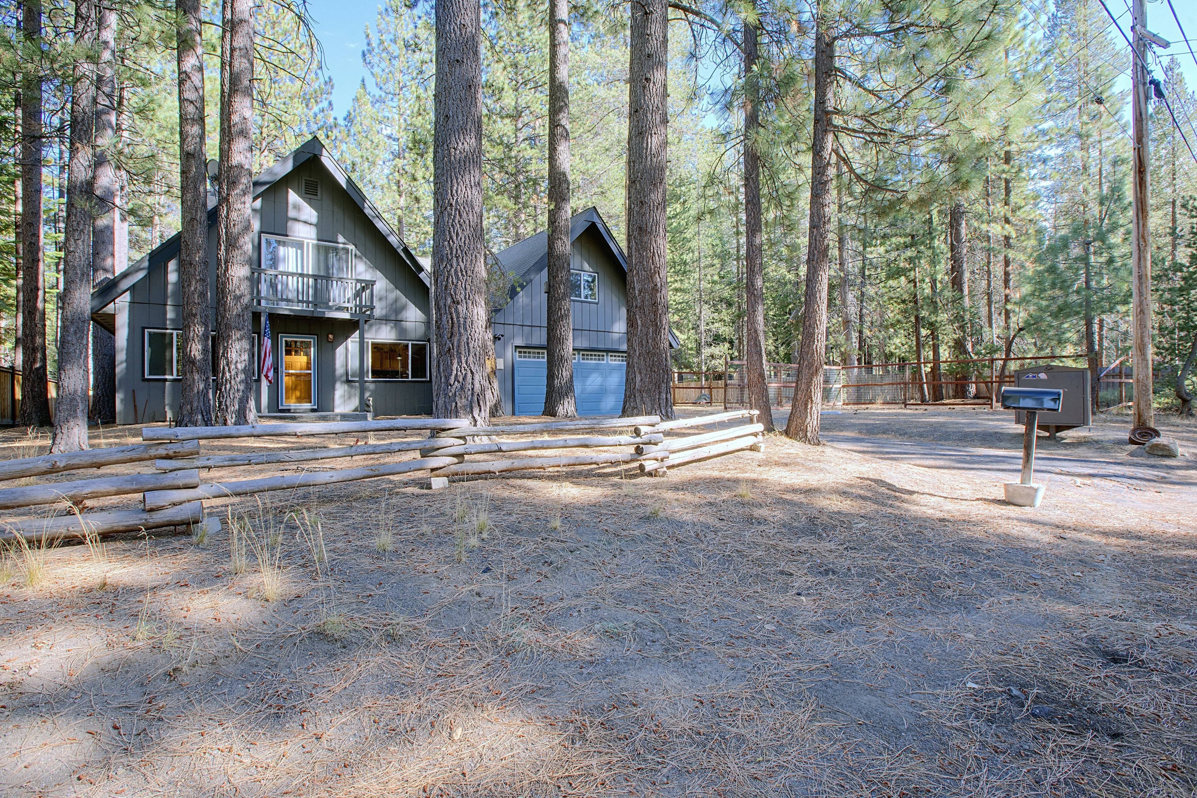 A cabin with a front porch, a garage, and a fenced yard.
